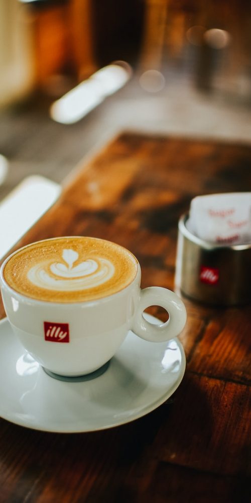 white ceramic cup with saucer on brown wooden table